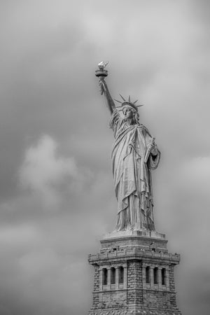 Liberty raises her torch above a stone pedestal beneath an overcast sky.