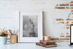 Black and white New York photograph of the Statue of Liberty under grey clouds.