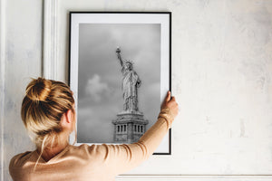 Crown, torch and draped robes of the Statue of Liberty against a pale sky.