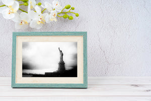 Liberty Island shoreline and monument beneath heavy grey clouds.