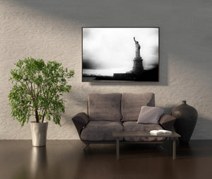 Monochrome harbor landscape with Liberty to the right and distant cranes to the left.