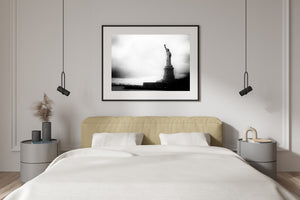 New York landmark silhouetted against pale clouds above dark water.