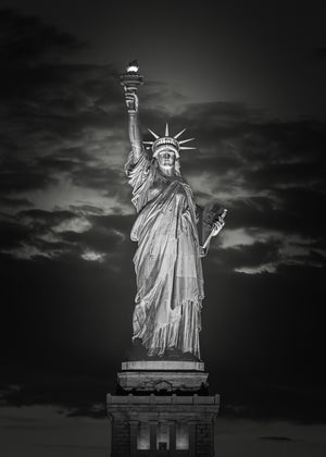 Statue of Liberty glows beneath a dramatic night sky.