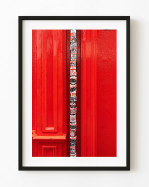 Sticker-covered Dublin drainpipe against a vivid red facade.