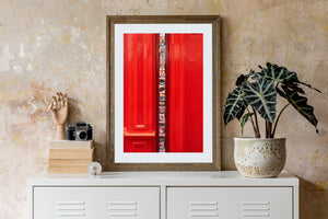 Black and white stickers create a vertical strip against a red building facade.