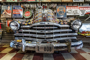 Chrome grille and round headlights on a Pontiac decorated with Route 66 stickers.