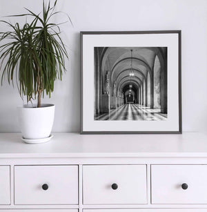 Stone statues stand along a vaulted passage with a glossy checkered floor.