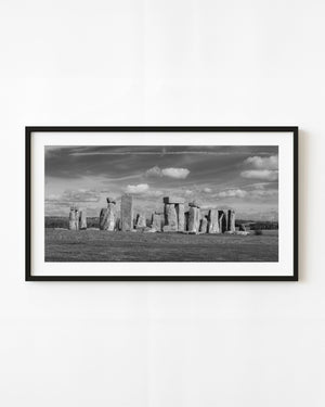 Stonehenge standing stones beneath scattered clouds in a black and white English landscape.