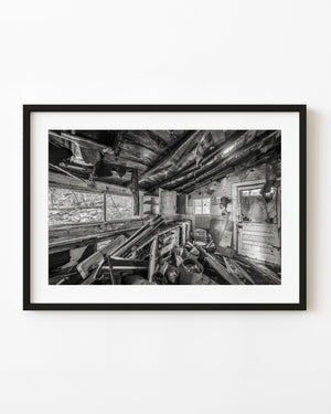 Ruined Stony Dell Resort kitchen with exposed rafters and scattered debris in black and white.