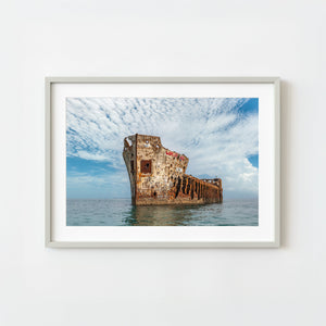 Framed photograph of a sunken ship with a cloudy sky background