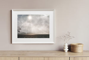 Antarctic seascape with drifting snow and a faint sun above the coast.