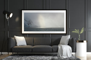Antarctic shoreline disappears into dense snowy mist beneath a faint glow.