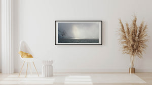 Soft light breaks through snowfall over an Antarctic bay.