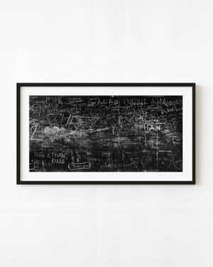Black and white photograph of layered chalk names and drawings on a Sydney graffiti wall.