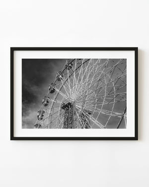 Sydney Ferris wheel spokes and gondolas against dark clouds in black and white.