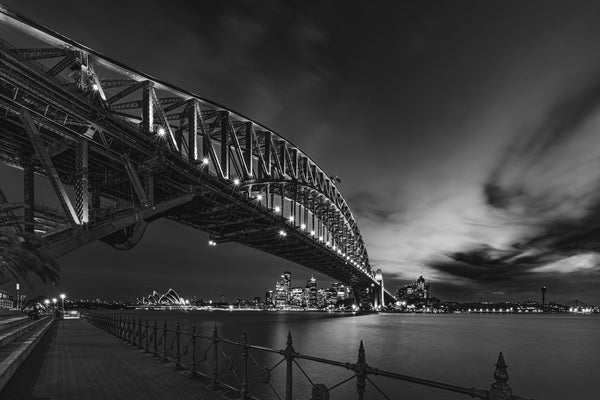 Black and white photo of Sydney Opera House under bridge