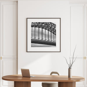 Dark bridge beams and repeating vertical lines contrast with soft grey clouds.