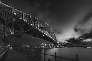 Starburst lights follow the steel arch of Sydney Harbour Bridge at night.
