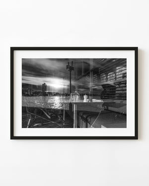 Sydney Harbour reflected across a restaurant window with table settings in black and white.