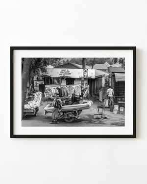 Tanzania roadside clothing market with a person beside a garment cart in black and white.