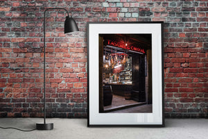 Tasca El Corral bar shelves and hanging meats seen through a stone-framed entrance.