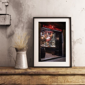Warm light and red signage contrast with dark wood at a Barcelona tavern.