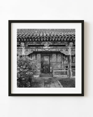 Temple of Appliques entrance in Ulaanbaatar with ornate woodwork and tiled eaves in black and white.