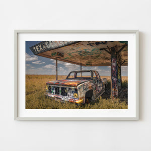 Abandoned graffiti covered pickup truck beneath old Texaco station