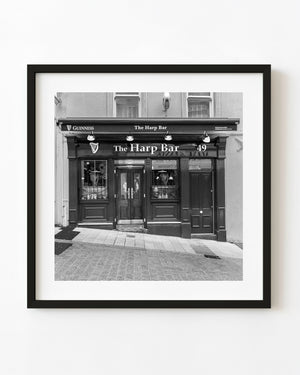 The Harp Bar Irish pub facade with dark wooden doors and Guinness signs in black and white.