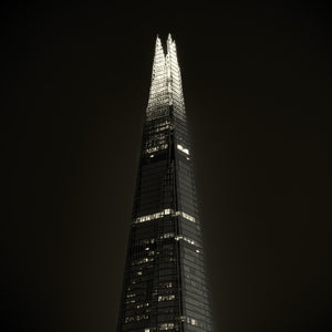 Bright pointed glass crown of The Shard rises above scattered office lights.
