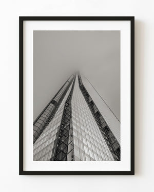 The Shard rises into dense London fog in a low-angle monochrome architectural photograph.