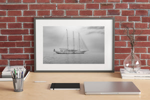 Quiet sailing yacht sits against a soft grey horizon beneath light cloud.
