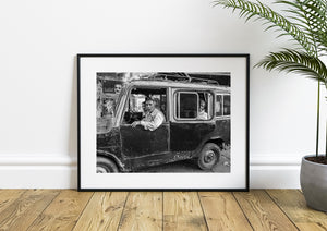 Black and white Indian street photograph of three men in a worn vehicle.