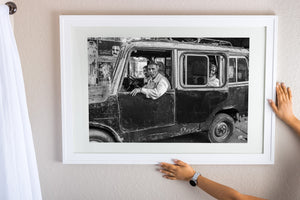 Weathered metal bodywork surrounds three men inside a roadside vehicle.