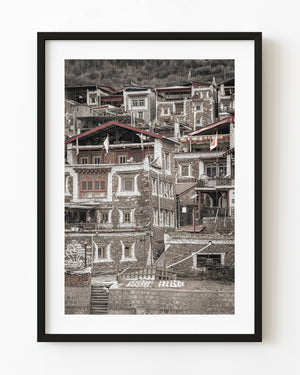 Tibetan hillside homes with stone walls, white window trim and red roof accents.