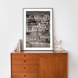 Weathered hillside dwellings with carved window details and scattered prayer flags.