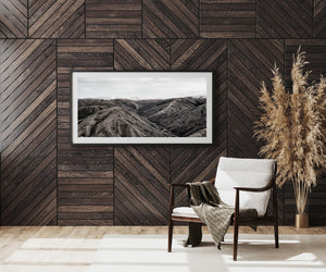 Monochrome mountain landscape with textured slopes and a winding central valley.