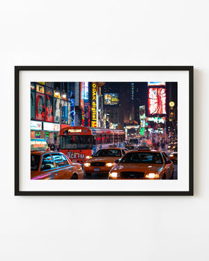 Yellow taxis and a bus beneath Times Square neon signs at night