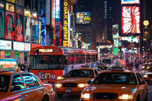 Times Square night traffic with yellow cabs and a city bus