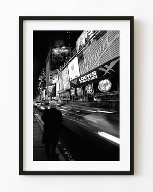 Woman beside blurred Times Square night traffic in black and white