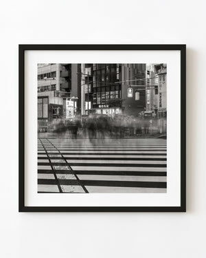 Motion-blurred pedestrians on a striped Tokyo crosswalk in black and white