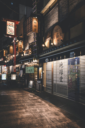 Tokyo night street with glowing signs and a painted metal shutter