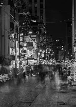 Tokyo night street with ghostlike pedestrians beneath glowing restaurant signs