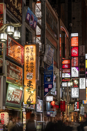 Tokyo night street with layered illuminated signs and blurred pedestrians
