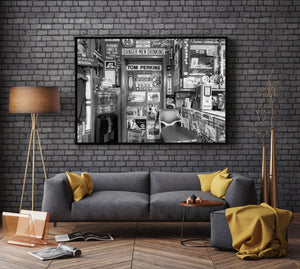 Black and white shop interior with a worn chair and densely arranged signs