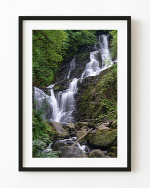 Torc Waterfall cascading over dark rocks through lush green Irish woodland