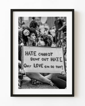 Seated Toronto G20 protester holding a sign about love and hate in black and white