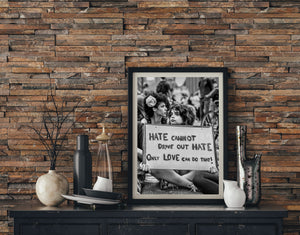 Monochrome protest scene with a sign reading that only love can drive out hate
