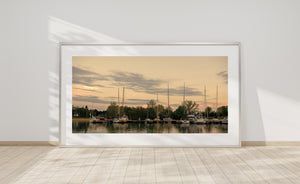 Moored boats and leafy trees beneath layered evening clouds in Toronto