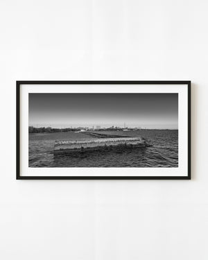 Toronto skyline beyond a waterfront breakwater in black and white